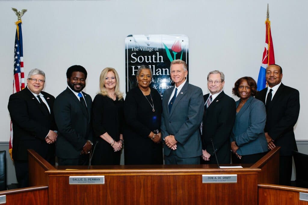 The Mayor and the Board of Trustees standing in the Village Hall