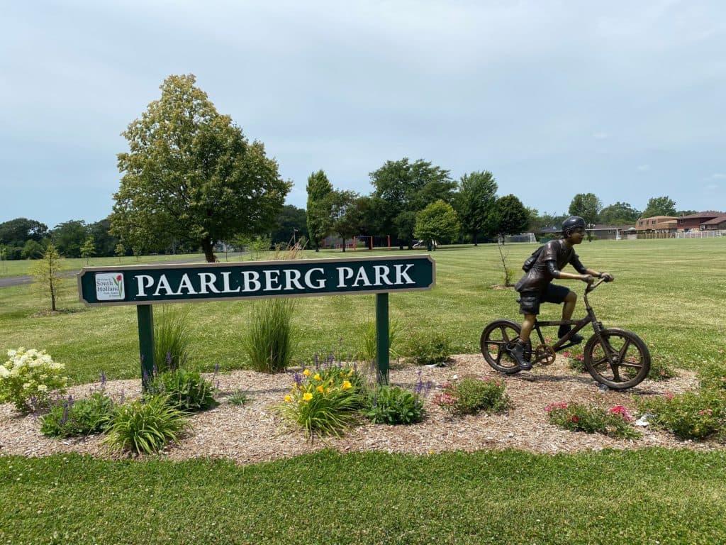 Paarlberg Park sign with flower bed and bicycle statue.