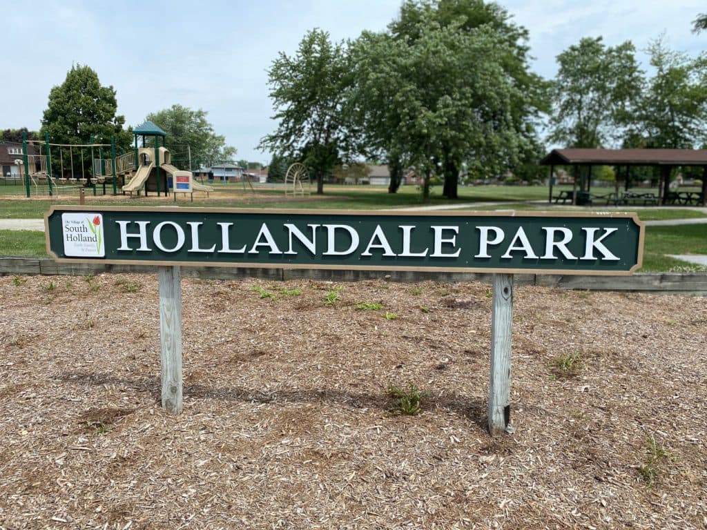 Hollandale Park sign with playground behind it